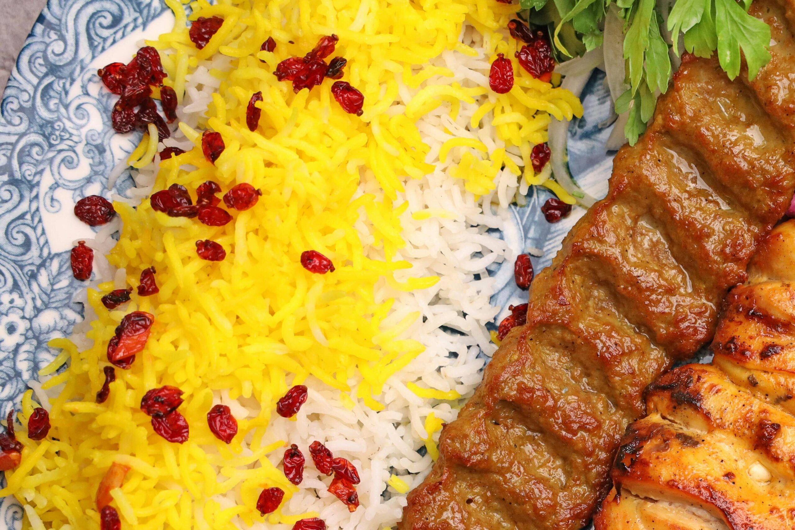 A flavorful Persian kebab dish with saffron rice, grilled meats, and vibrant sides.