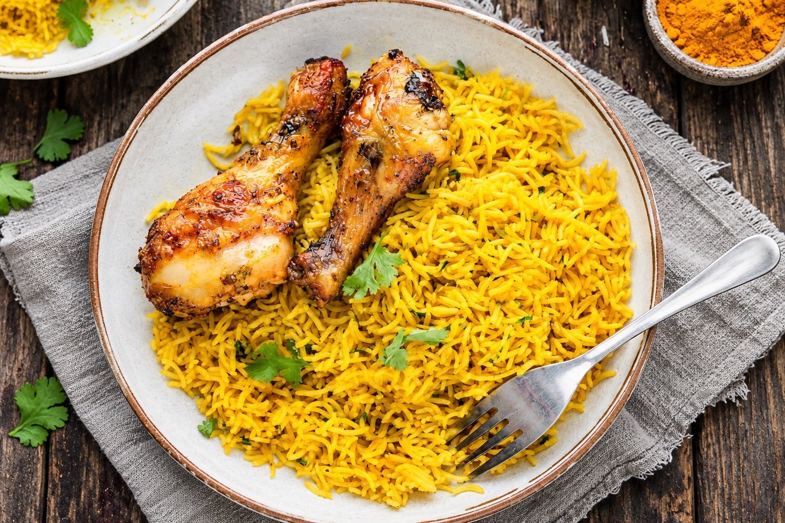 Golden turmeric rice served with grilled chicken on a ceramic plate